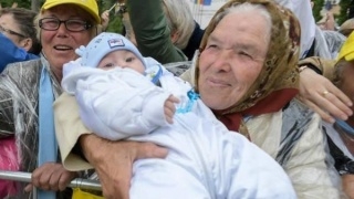 O bătrână din România cu nepotul în braţe în noua carte de rugăciuni a Papei Francisc
