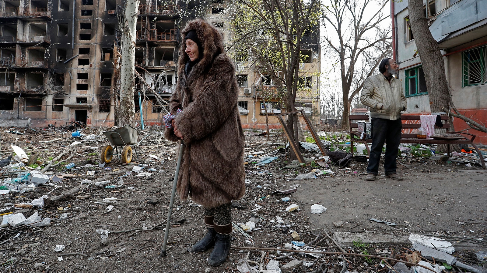Localnicii stau într-o curte în apropierea unei clădiri rezidențiale distruse din Mariupol Ucraina
