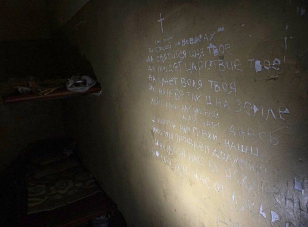 Rugăciunea Tatăl nostru scrijelită pe pereții unei camere de tortură